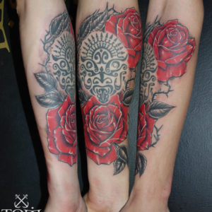 Rose rosse che si intrecciano ad un tatuaggio polinesiano