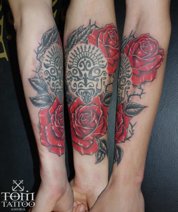 Rose rosse che si intrecciano ad un tatuaggio polinesiano